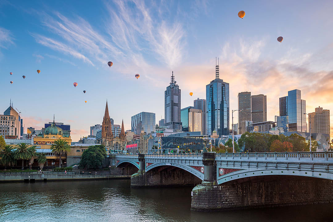 The Melbourne city skyline with hot air balloons floating in the sky.