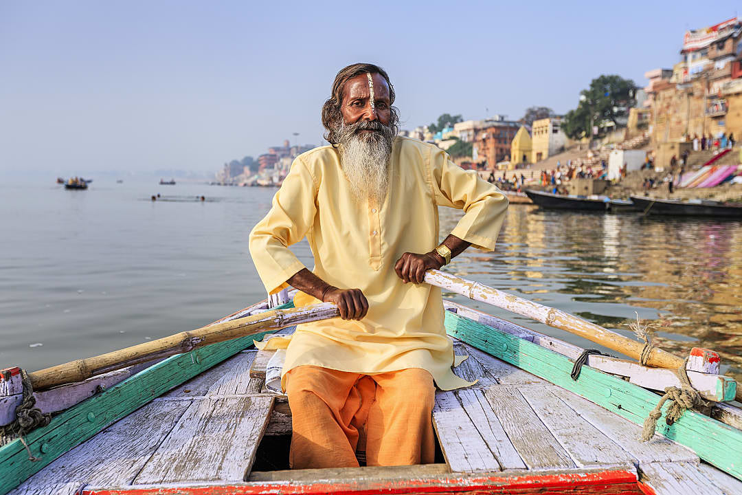 Senior sadhu sitting in wooden boat on the Ganga river