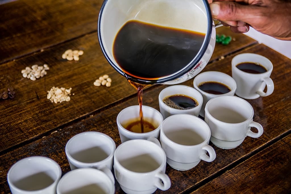 Coffee being poured into small white cups for tasting in Colombia