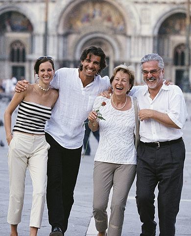 Smiling family strolls together through historic European city plaza.