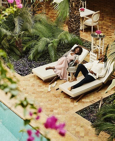 Couple relaxes on poolside loungers surrounded by lush tropical plants.