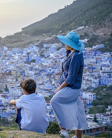 Mother and son admire panoramic view of colorful hillside town.