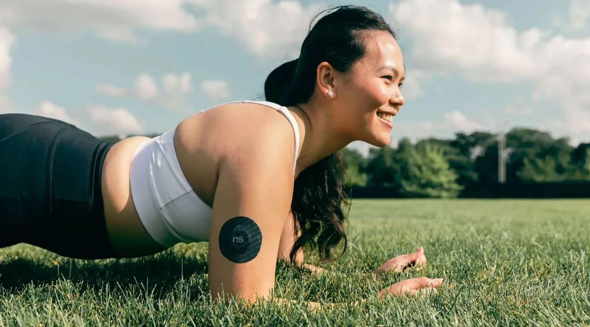 A woman wearing a glucose sensor exercises outdoors