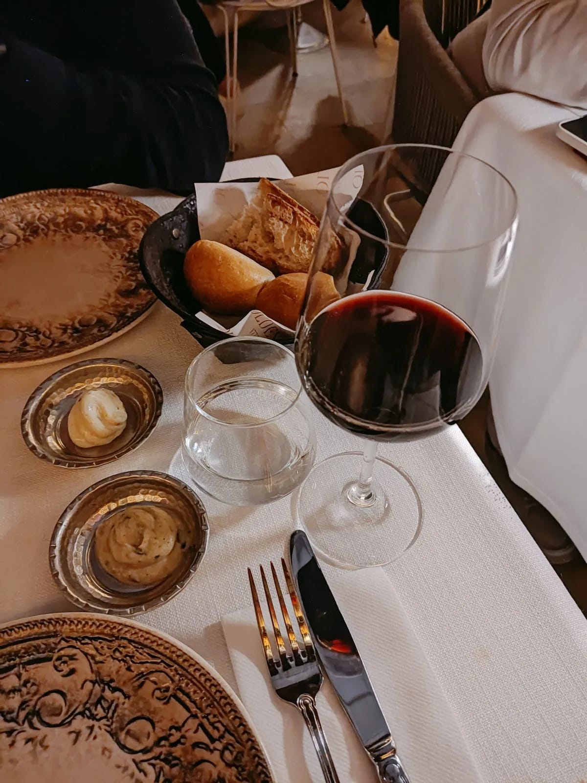 A glass of red wine beside a restaurant meal