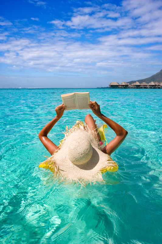 woman reading on raft in turquoise waters