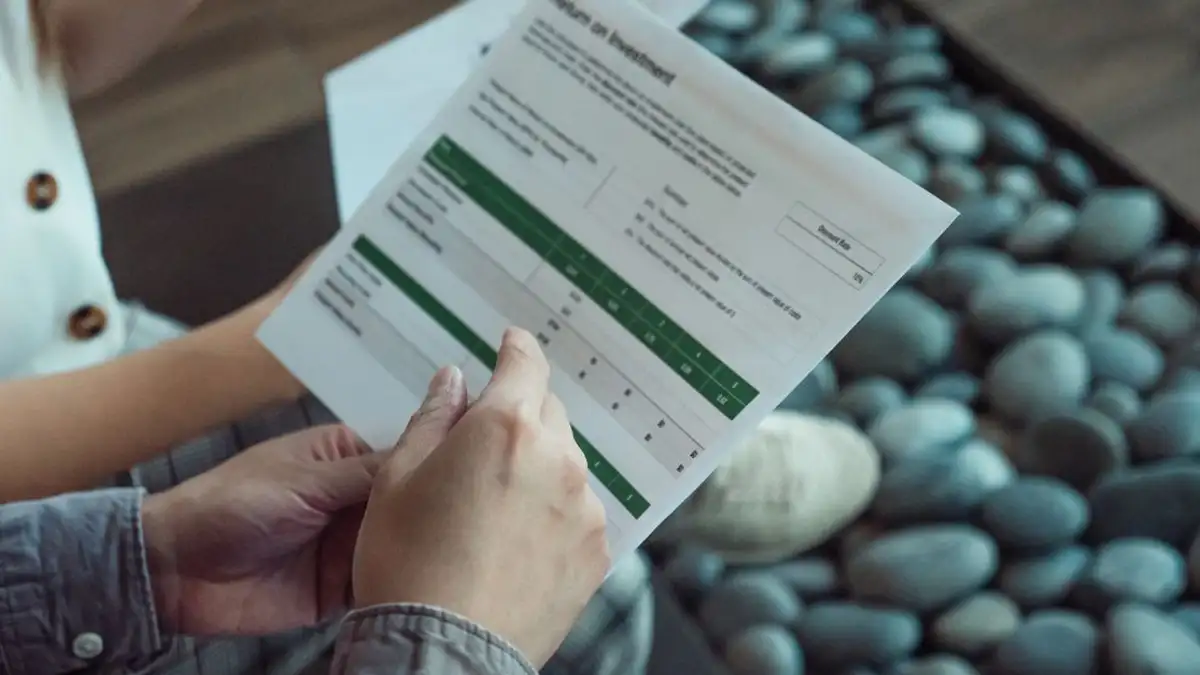 Dua orang mendiskusikan dokumen keuangan yang menunjukkan data kerja sama investasi.