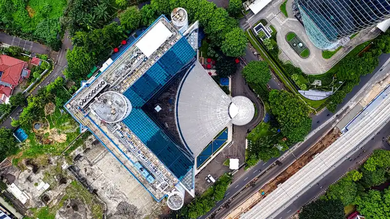 Foto drone yang menangkap arsitektur yang berwarna-warni dan kehijauan Jakarta, Indonesia.