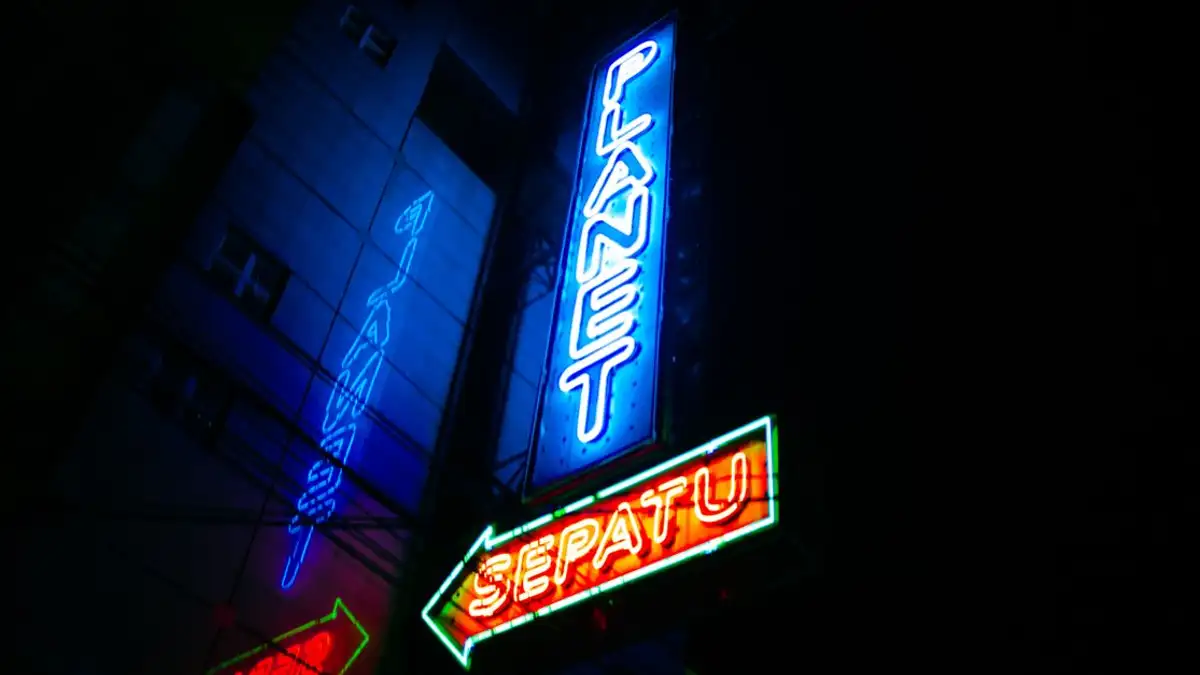 Papan tanda neon yang cerah menerangi pemandangan malam perkotaan di Kota Garut, Indonesia.