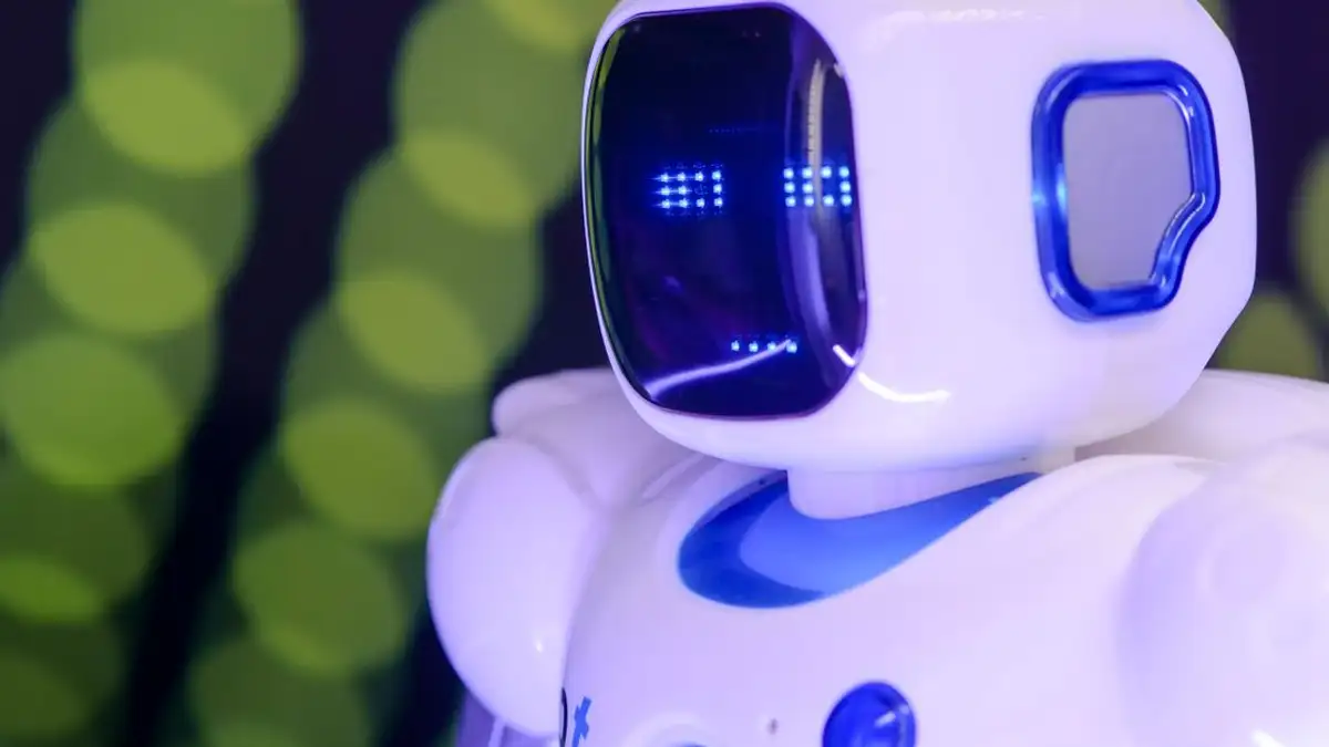 Close-up robot humanoid modern dengan fitur biru yang bercahaya di latar belakang abstrak hijau.