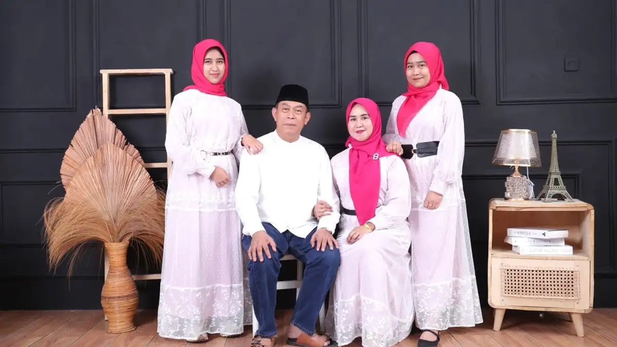 Empat anggota keluarga berpose mengenakan pakaian tradisional serasi di dalam ruangan.