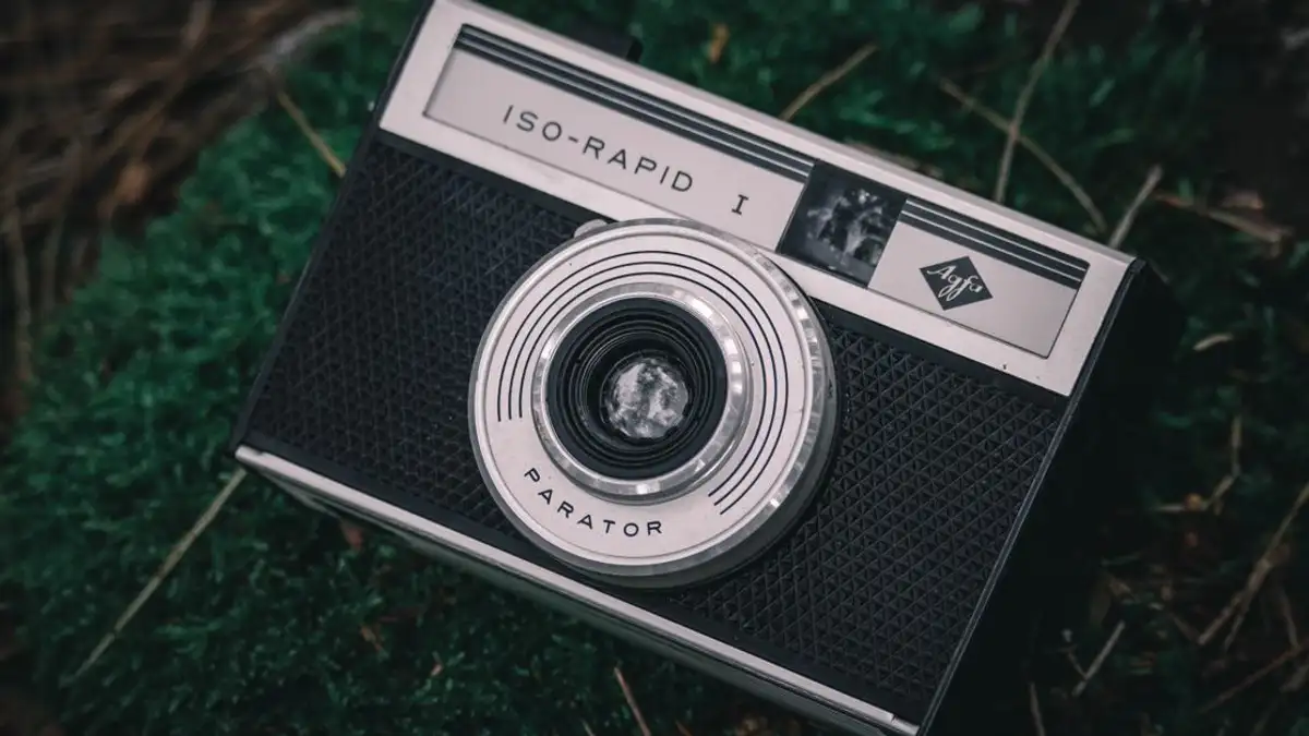 Kamera ISO-Rapid I jadul dengan desain retro yang tergeletak di atas rumput, membangkitkan nostalgia.