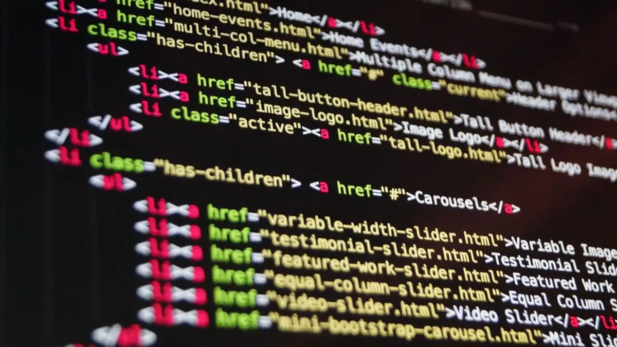 Close-up kode HTML yang disorot dalam warna cerah di monitor komputer.