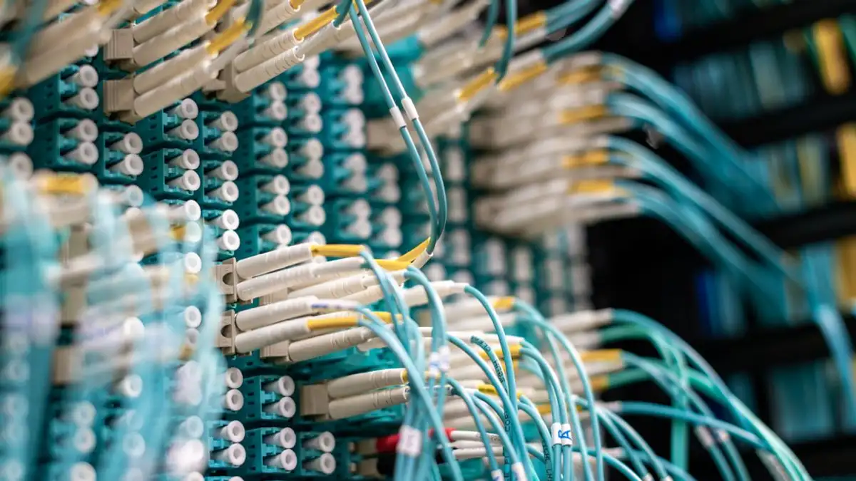 Tampilan detail kabel serat optik yang terhubung ke papan patch di pusat data.