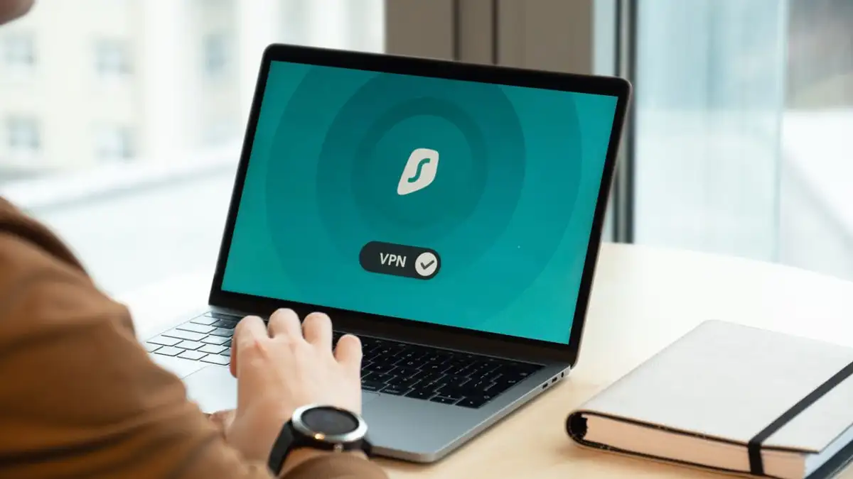 Individu menggunakan aplikasi VPN di laptop di meja dalam setting kantor modern.