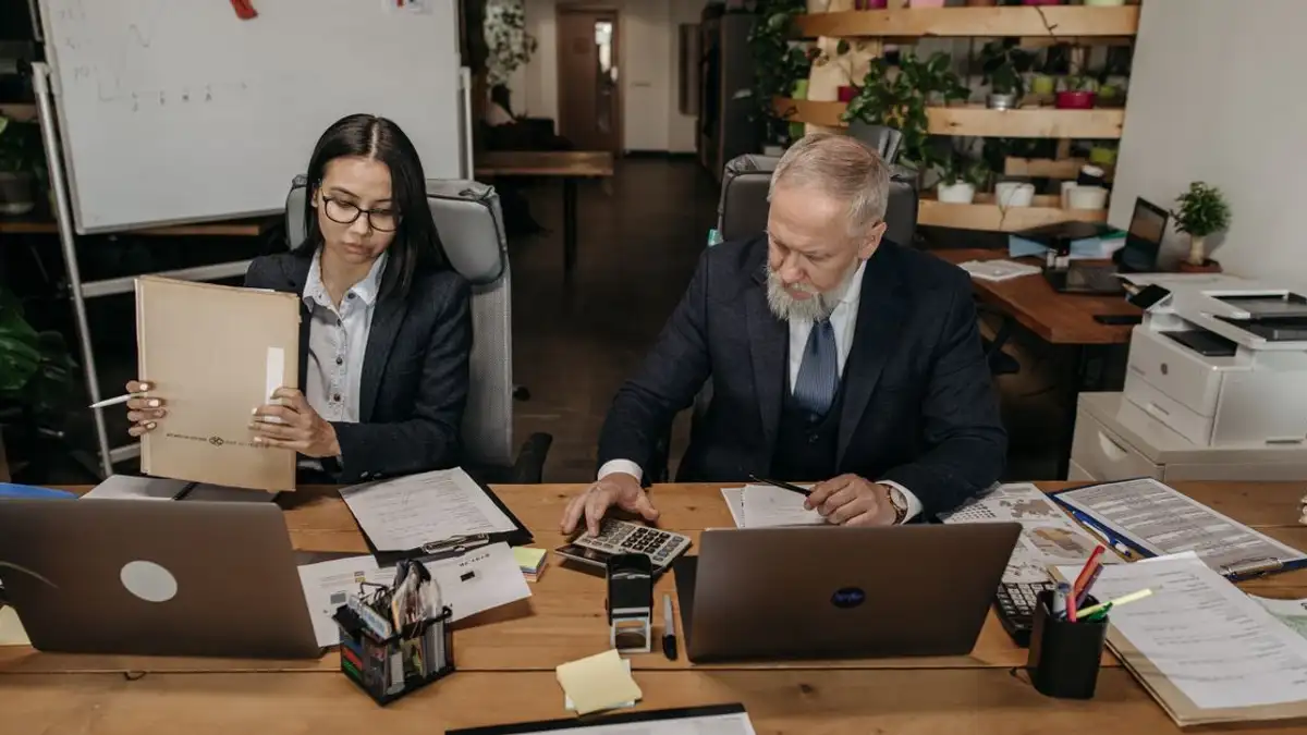 Profesional bisnis di kantor modern yang bekerja secara kolaboratif di meja dengan laptop.