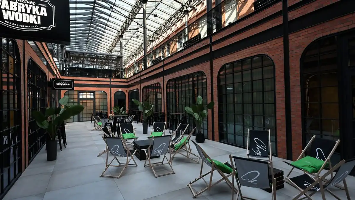 Interior Museum Pabrik Vodka Kraków dengan tempat duduk dan atap kaca.
