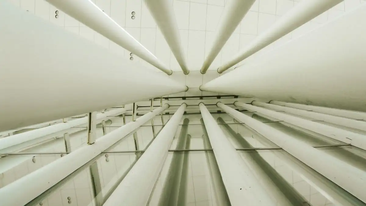 Tampilan ke atas kolom interior modern dalam ruang berstruktur geometris.