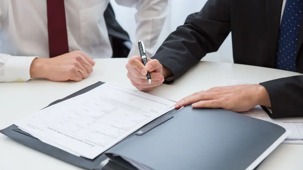 Dua profesional menandatangani kontrak pada pertemuan bisnis di kantor.