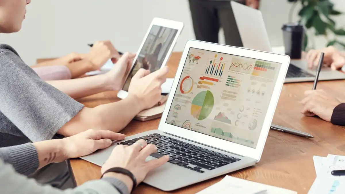 Rekan kerja menganalisis grafik data di laptop selama pertemuan tim.