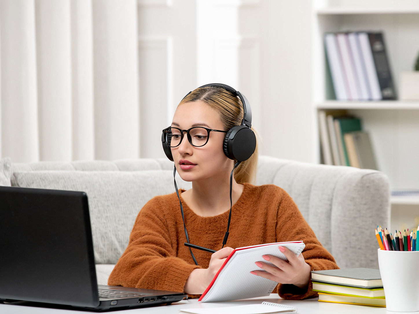 Student studying for LSAT online with 1-to-1 tutoring using headphones, laptop, and notebook for law school admission test preparation