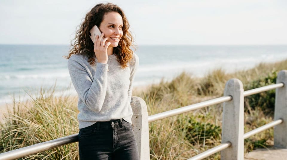 Jennie Stowe taking a call on a path above the beach