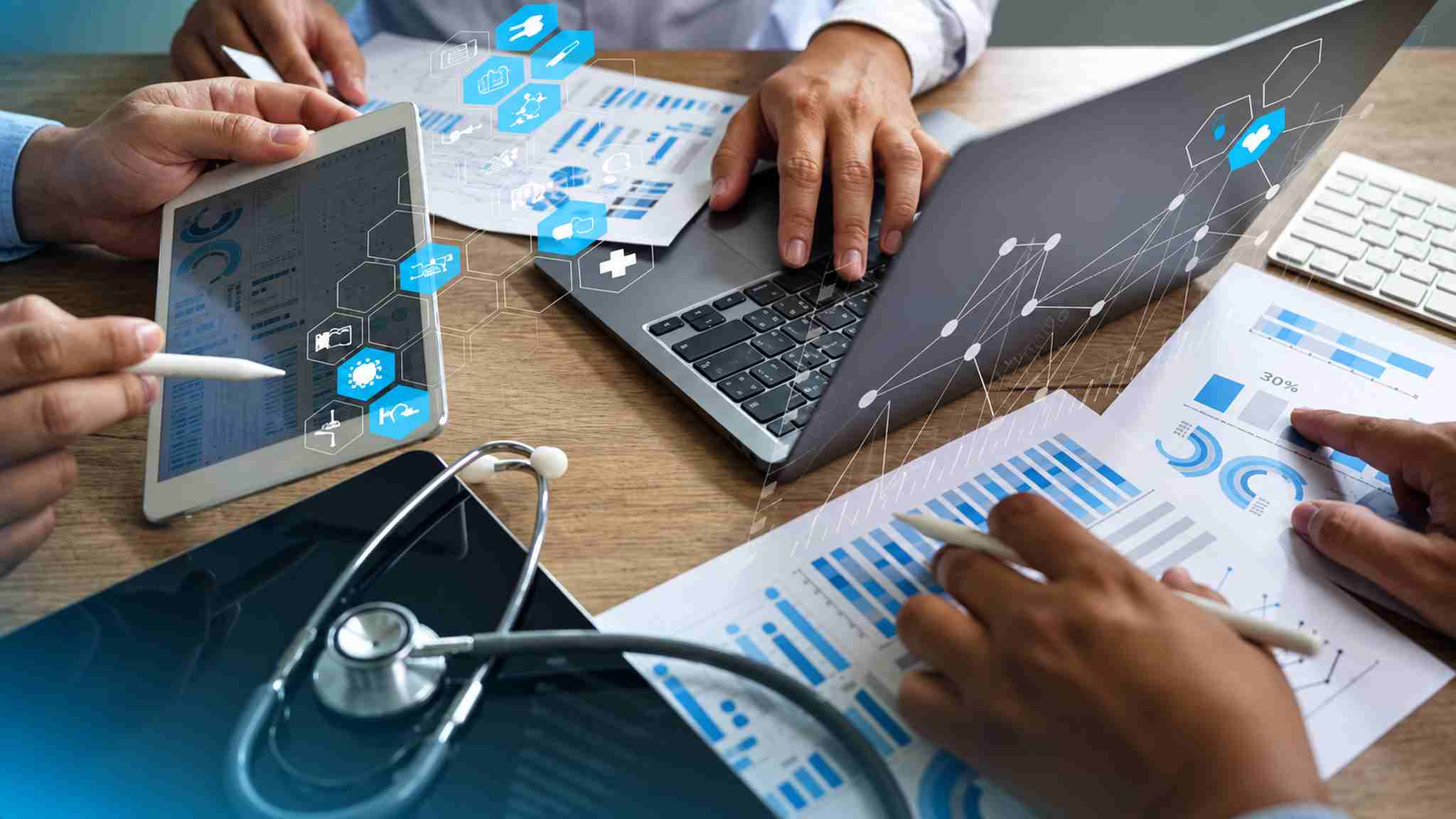 Healthcare professionals analyzing digital data on tablets and laptops with medical charts, illustrating non-clinical careers in Kerala hospitals.
