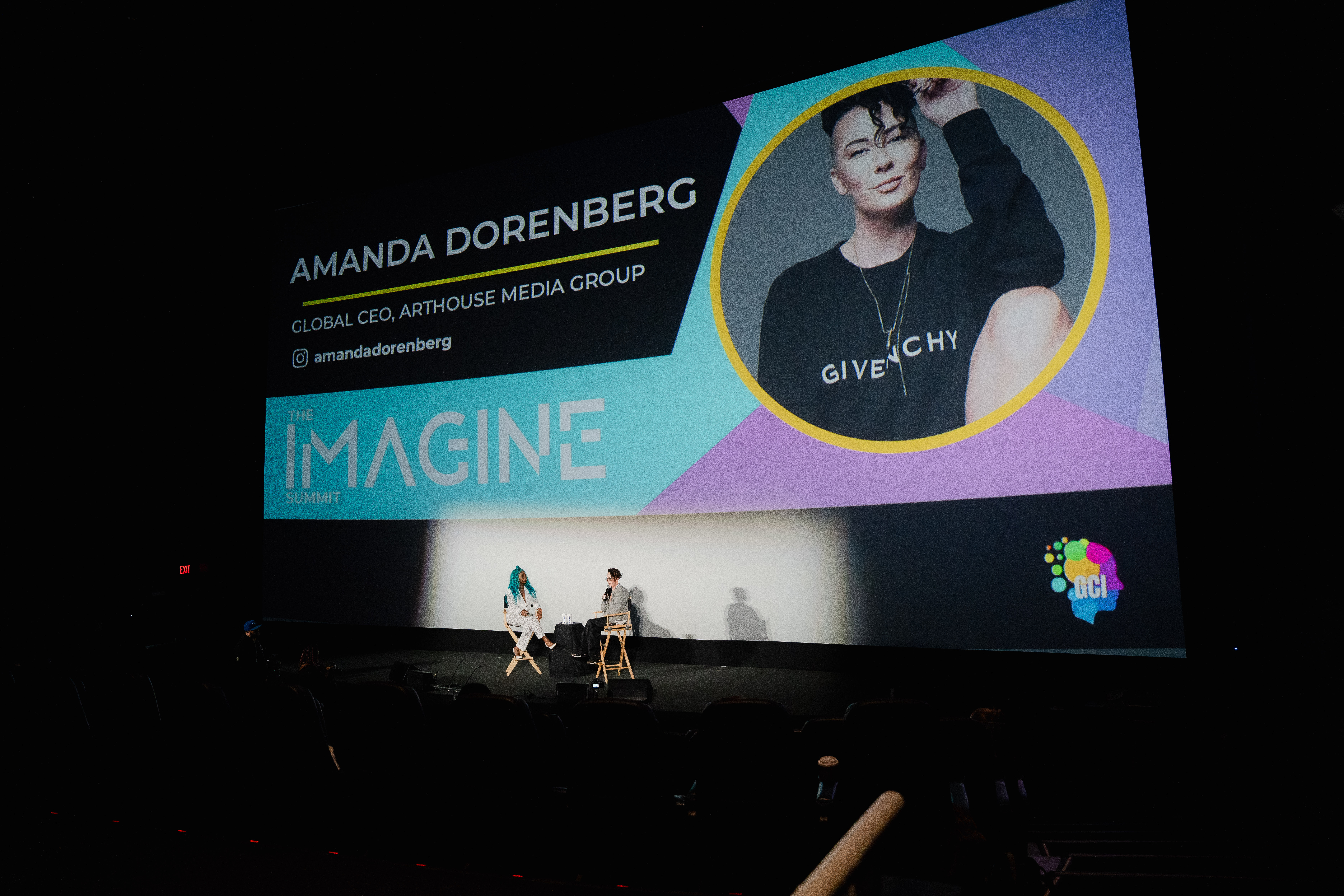 Vanessa Craft speaking at Imagiin Summit on stage with projection screen behind.