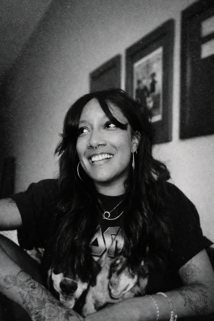 Woman with long dark hair wearing black t-shirt, black and white portrait.