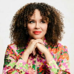 Vanessa Craft - woman with curly brown hair wearing colorful patterned jacket.