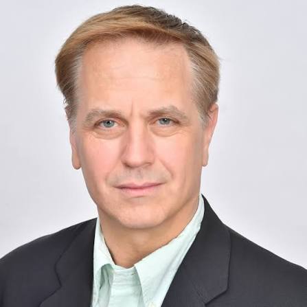 Man in professional business attire wearing dark jacket and light blue shirt.