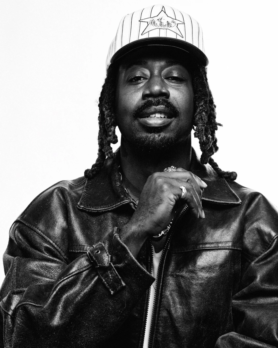Nana Kwabena — black-and-white portrait wearing a white cap and black leather jacket